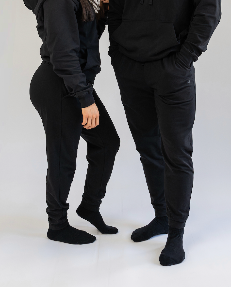 Two people wearing black tracksuits on a white background