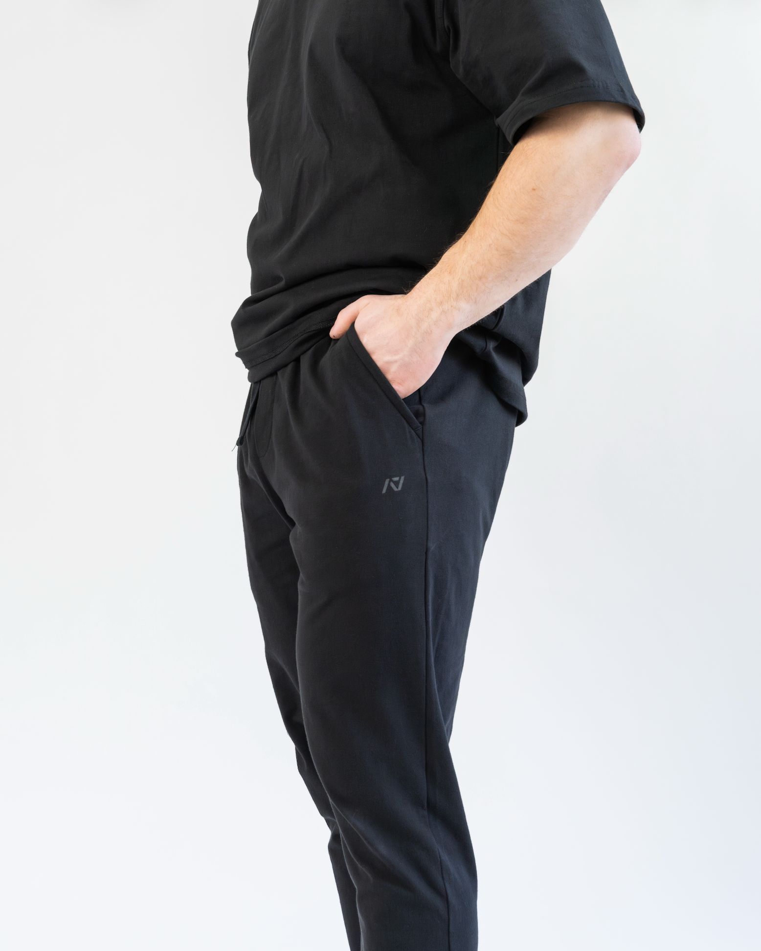 Person wearing black athletic pants and shirt on a white background