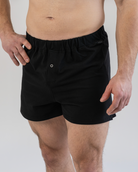 Person wearing black boxer shorts on a plain background