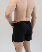 Person wearing black boxer shorts on a plain background
