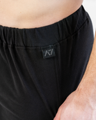 Black boxer shorts with a brand logo on the waistband against a neutral background