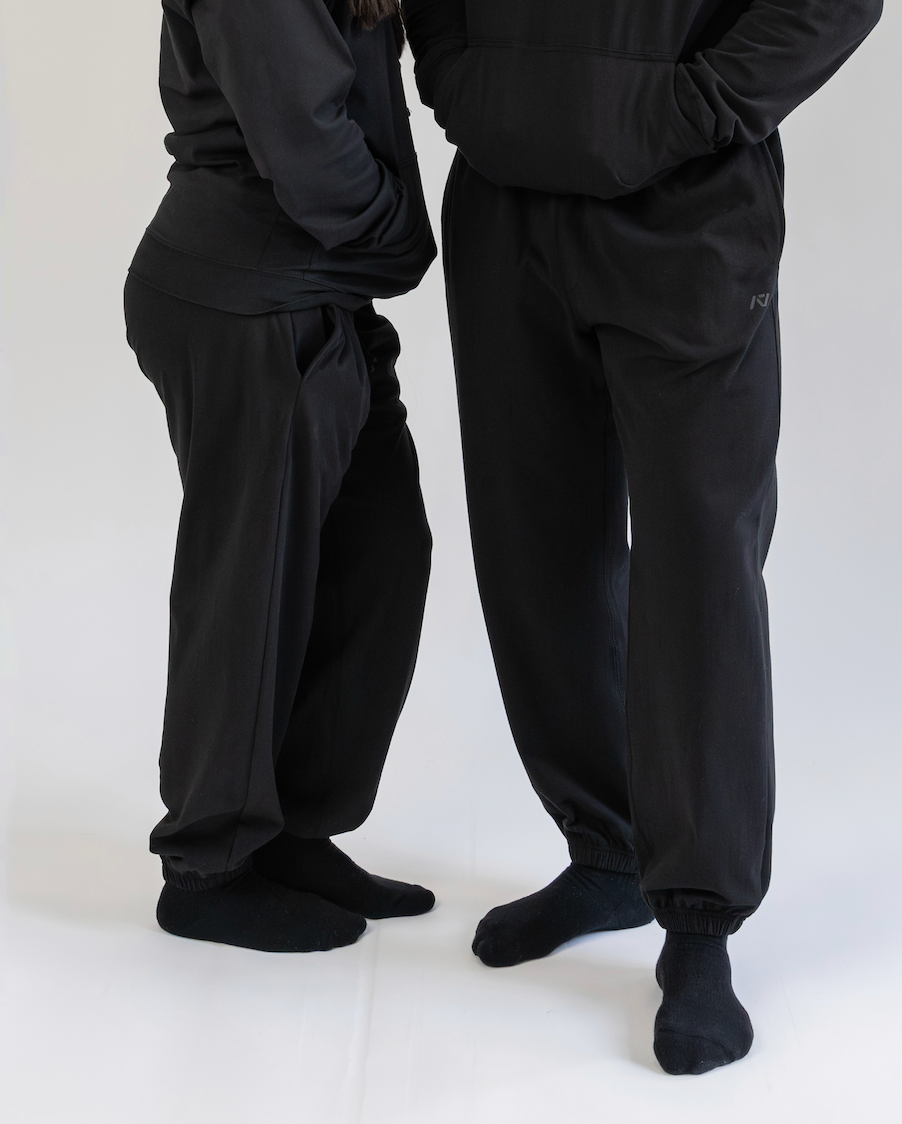 Two people wearing black pants and socks on a white background