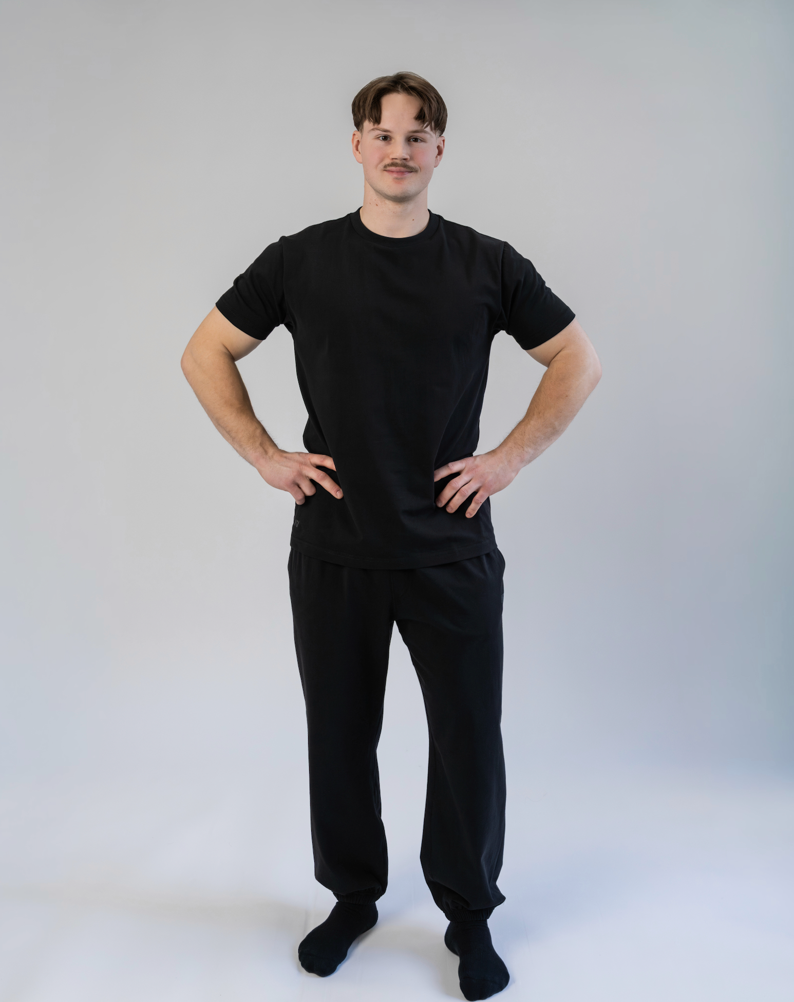Person wearing a black t-shirt and black pants on a white background