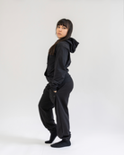 Person wearing a black hoodie and pants on a white background