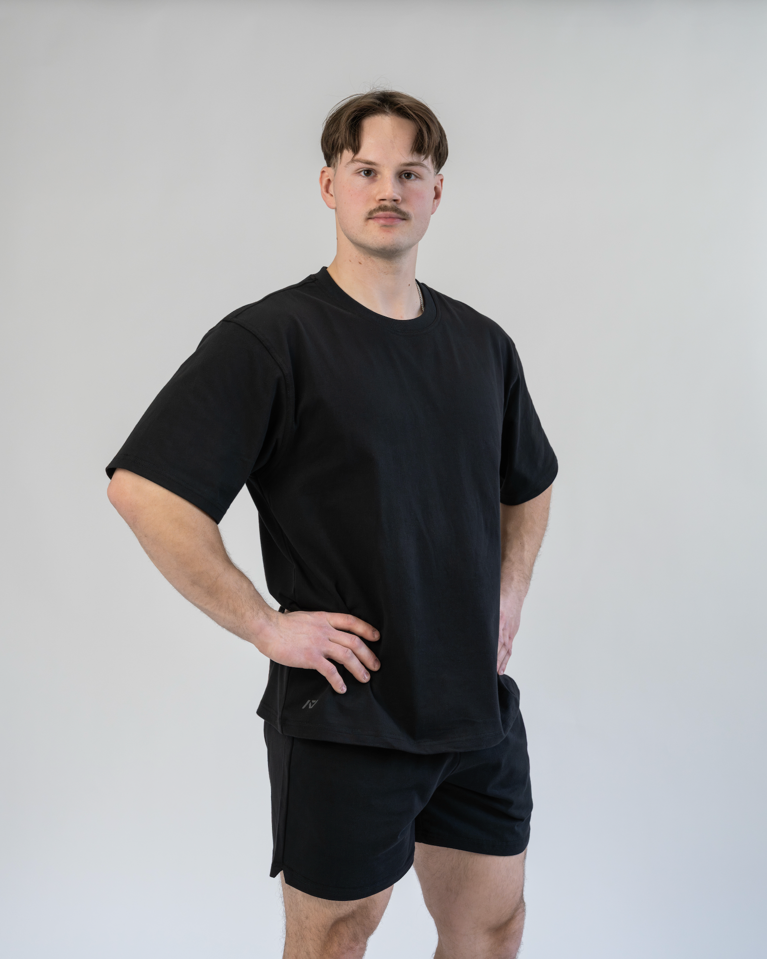 Man wearing a black t-shirt and shorts against a plain background