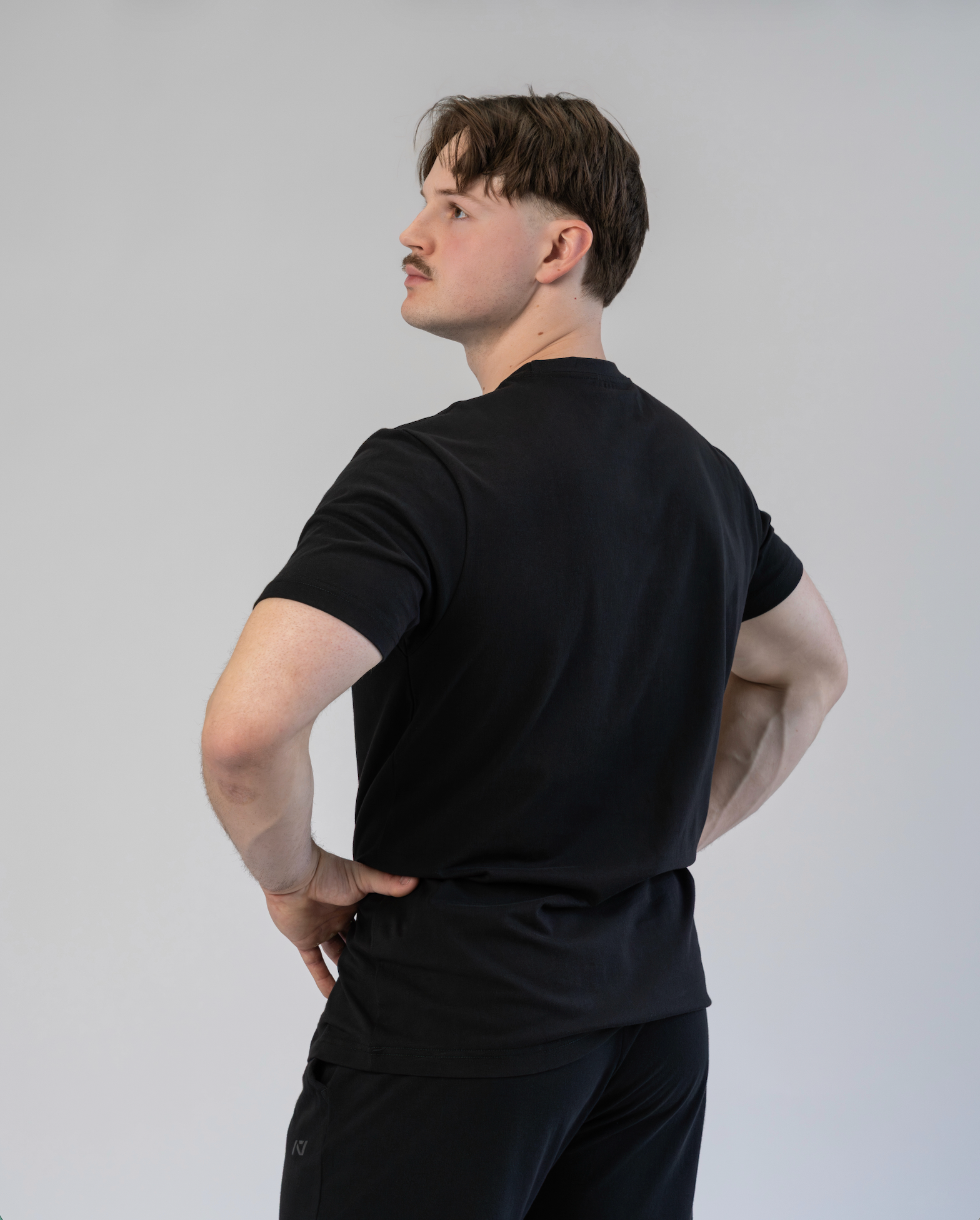Person wearing a black t-shirt and pants against a plain background