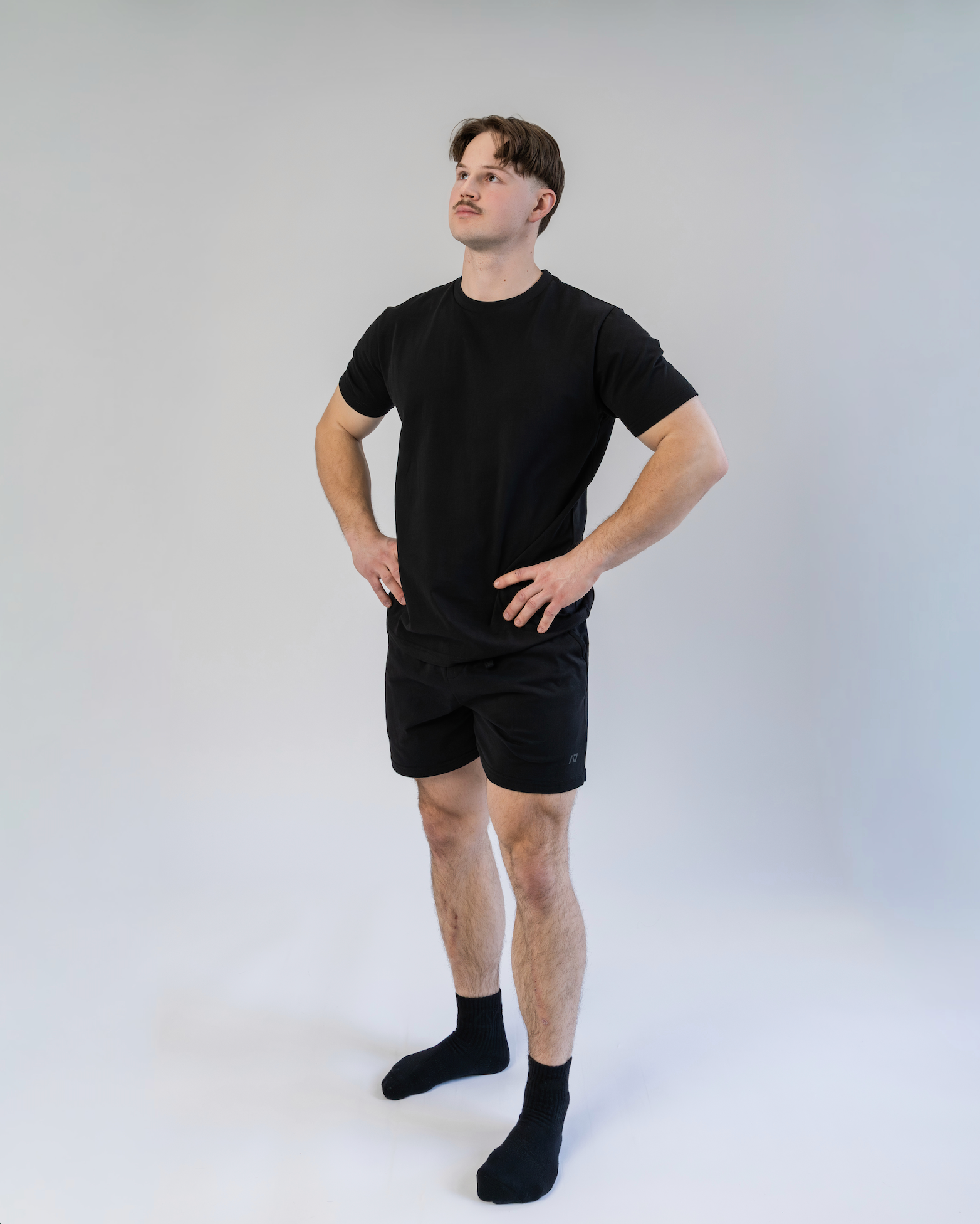 Person wearing a black t-shirt and shorts set on a white background