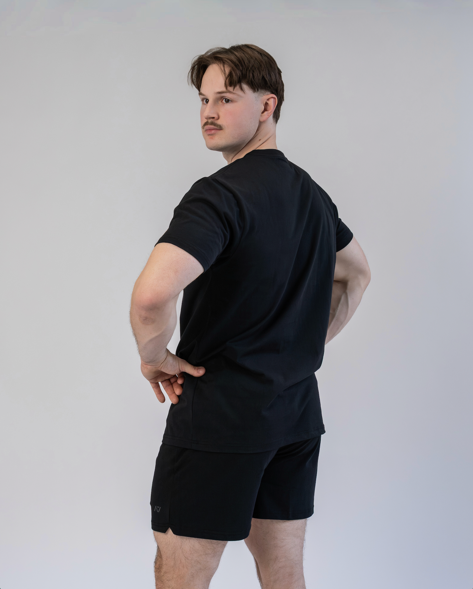 Man wearing a black t-shirt and shorts against a plain background